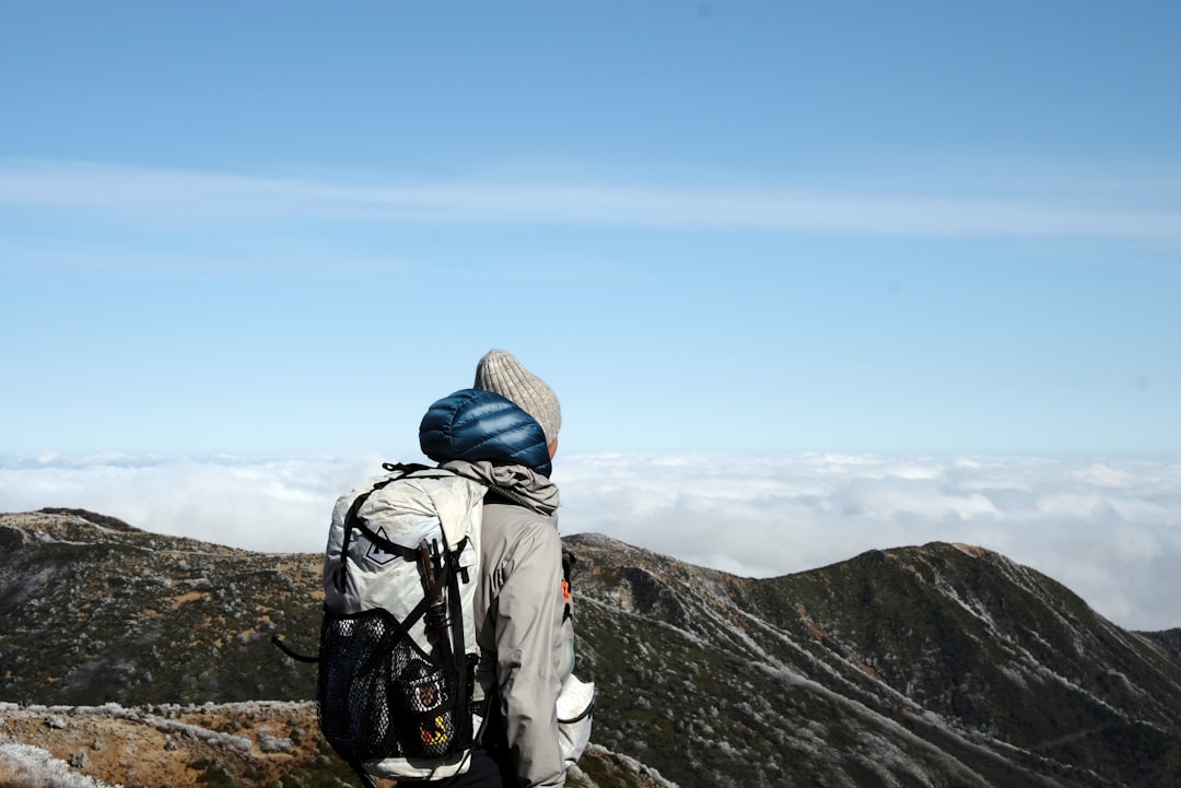寒い山でベースレイヤーを着て登山する50代のイメージ