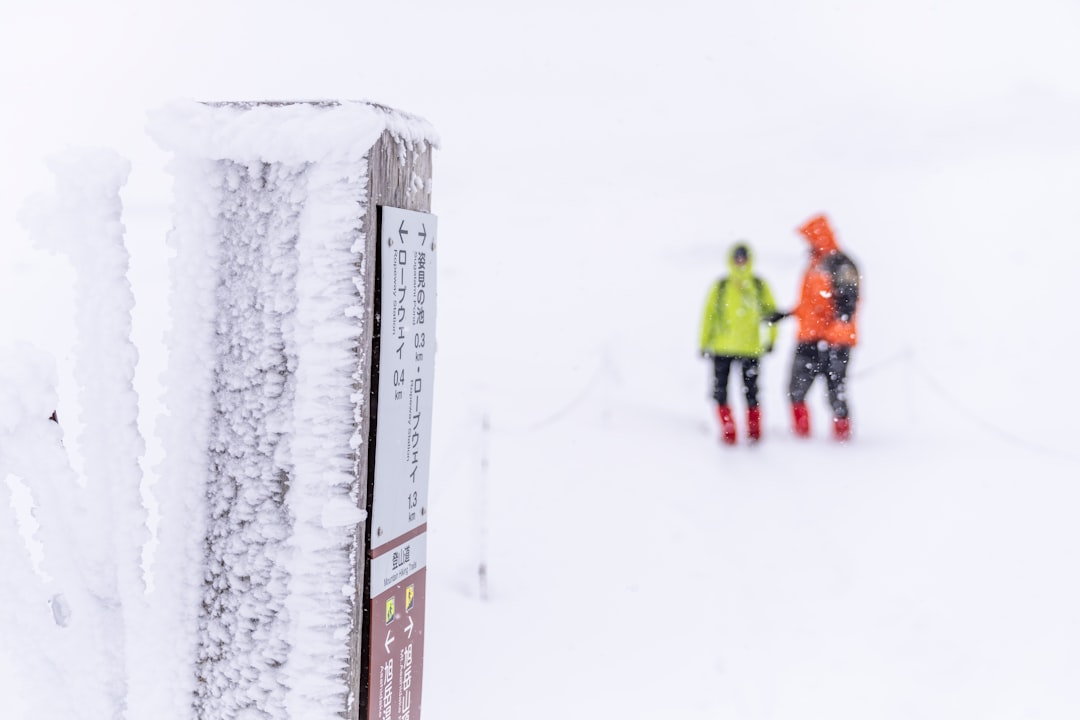 雪の山を歩く登山者2名