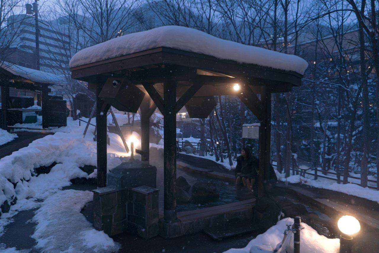 雪の舞う屋根付き露天風呂