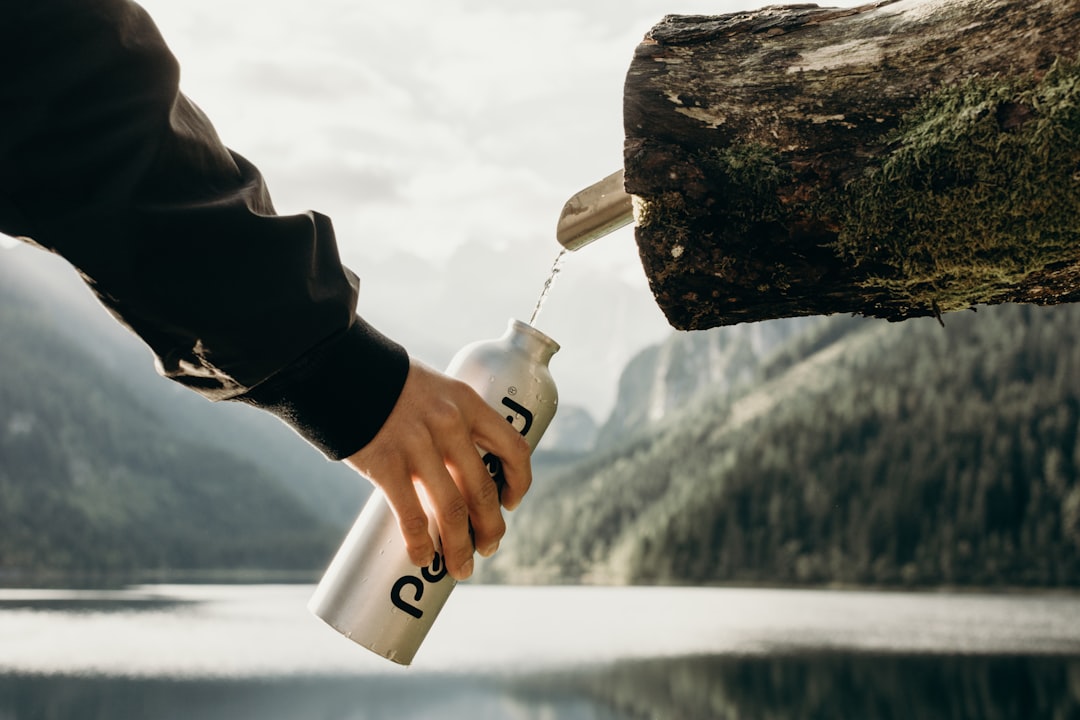 山の水場でボトルを掲げる登山者