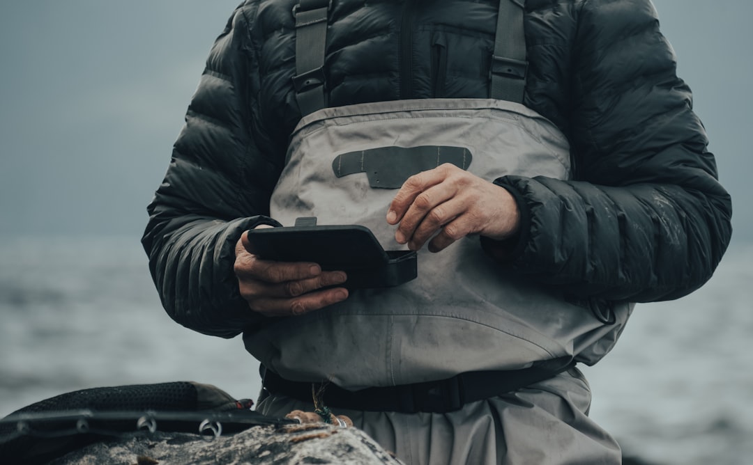 アウトドアウェアでスマートフォンを持つ人