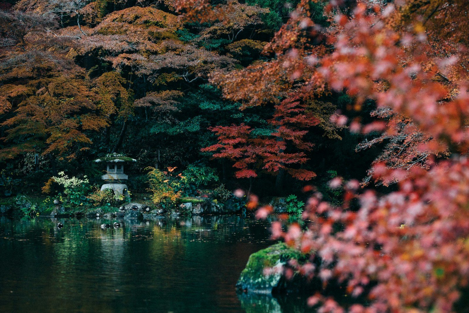 池のほとりに立つ塔と色づいた木々