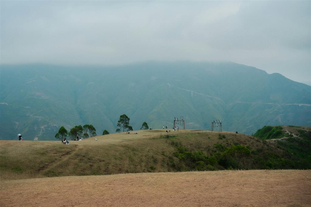 草原の稜線を歩く登山者と連なる山々