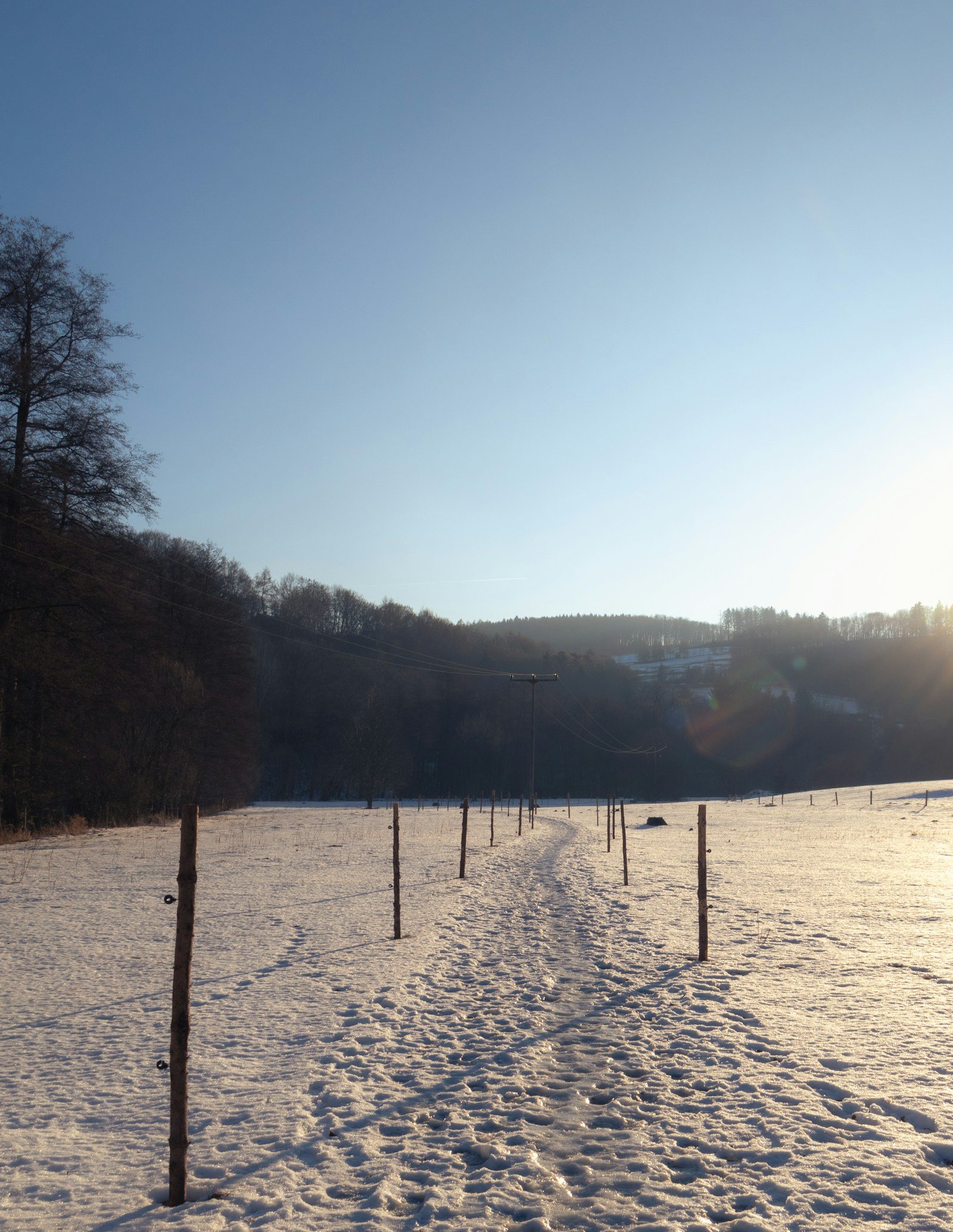 雪の残る道と夕暮れの丘
