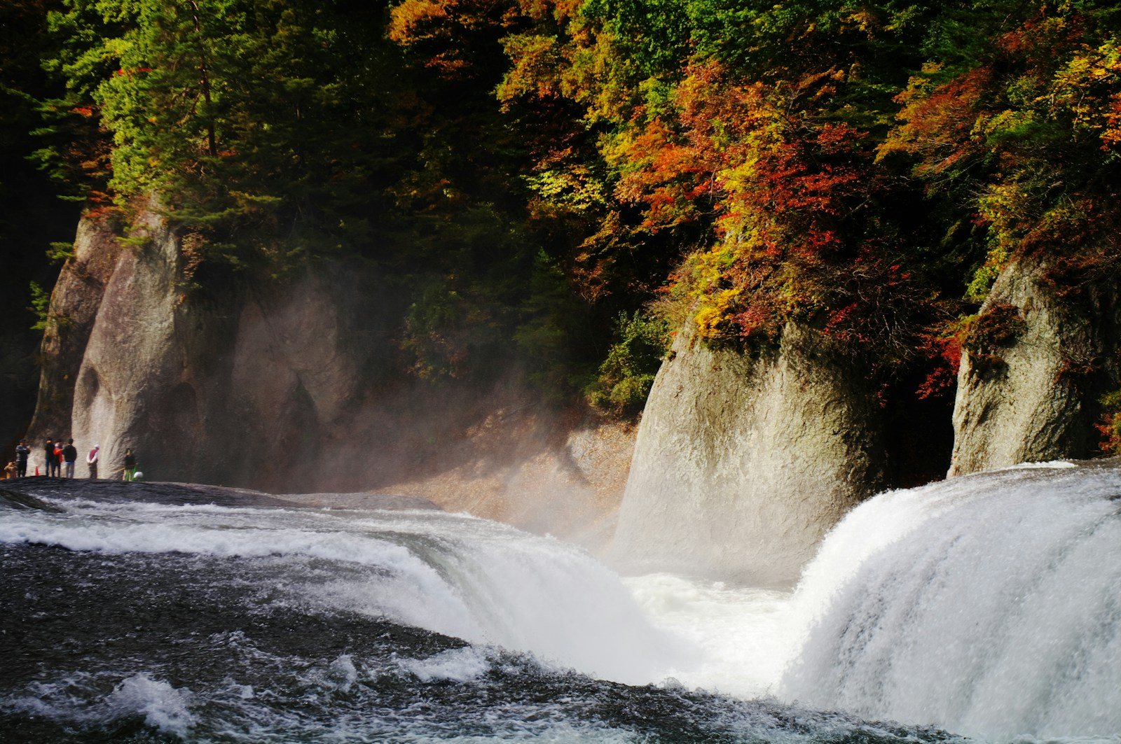 岩の割れ目を流れ落ちる滝と紅葉