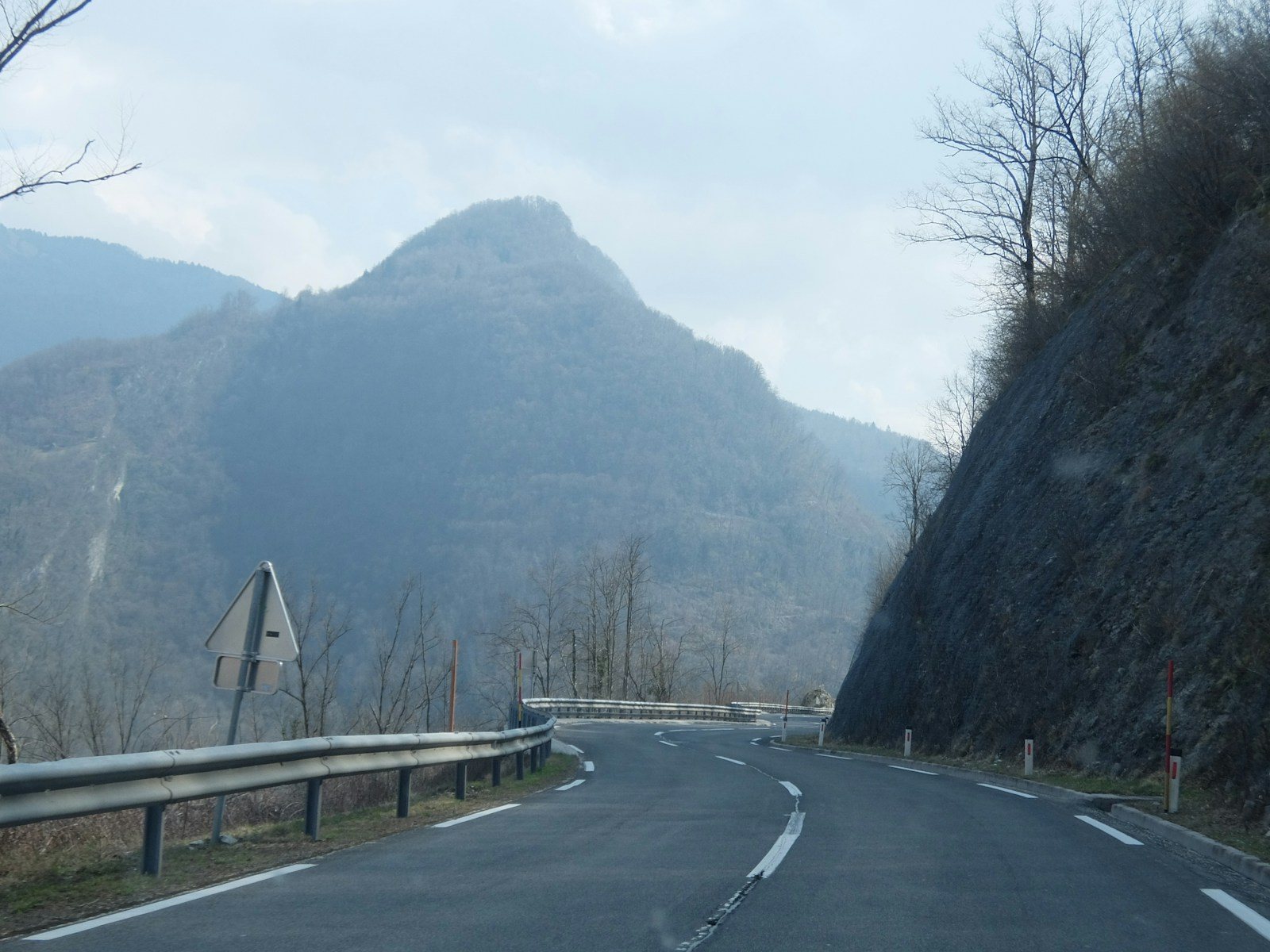 葉を落とした木々の間を曲がる山道