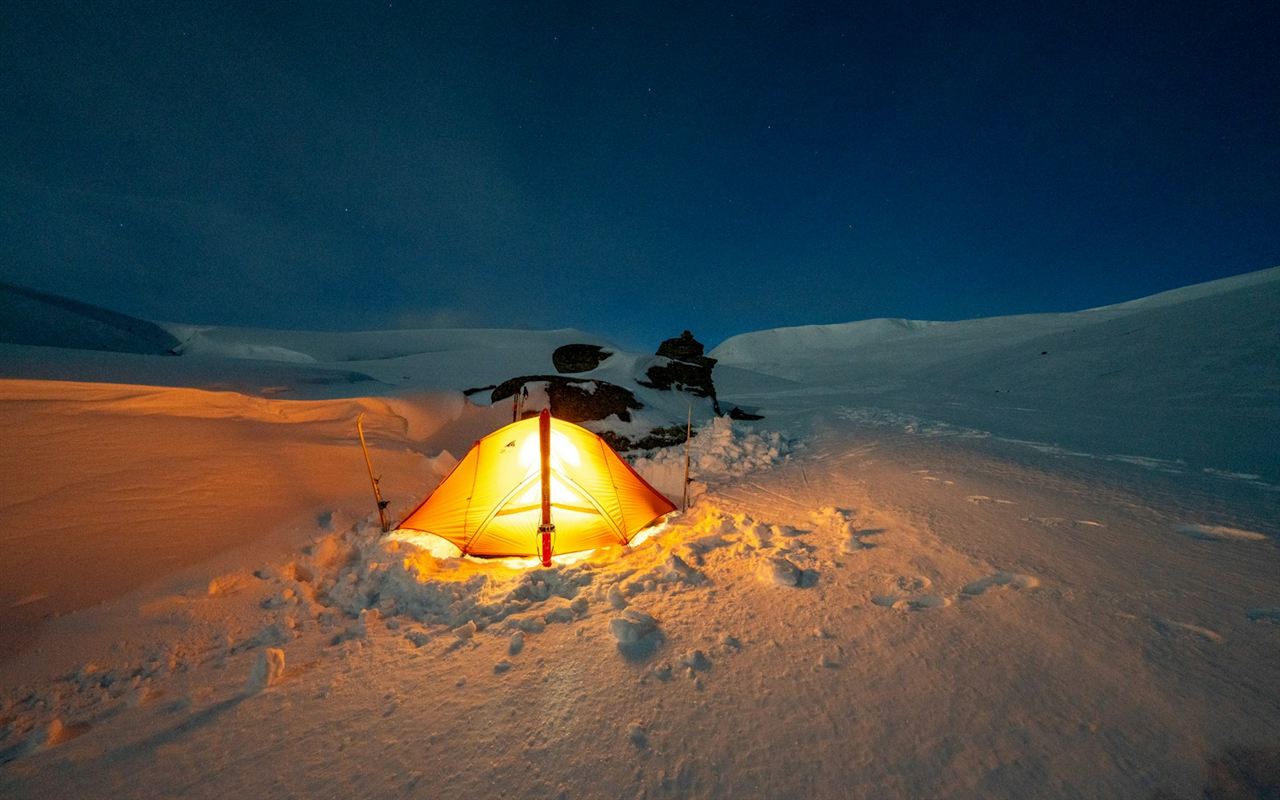 夜の雪原で光るテント