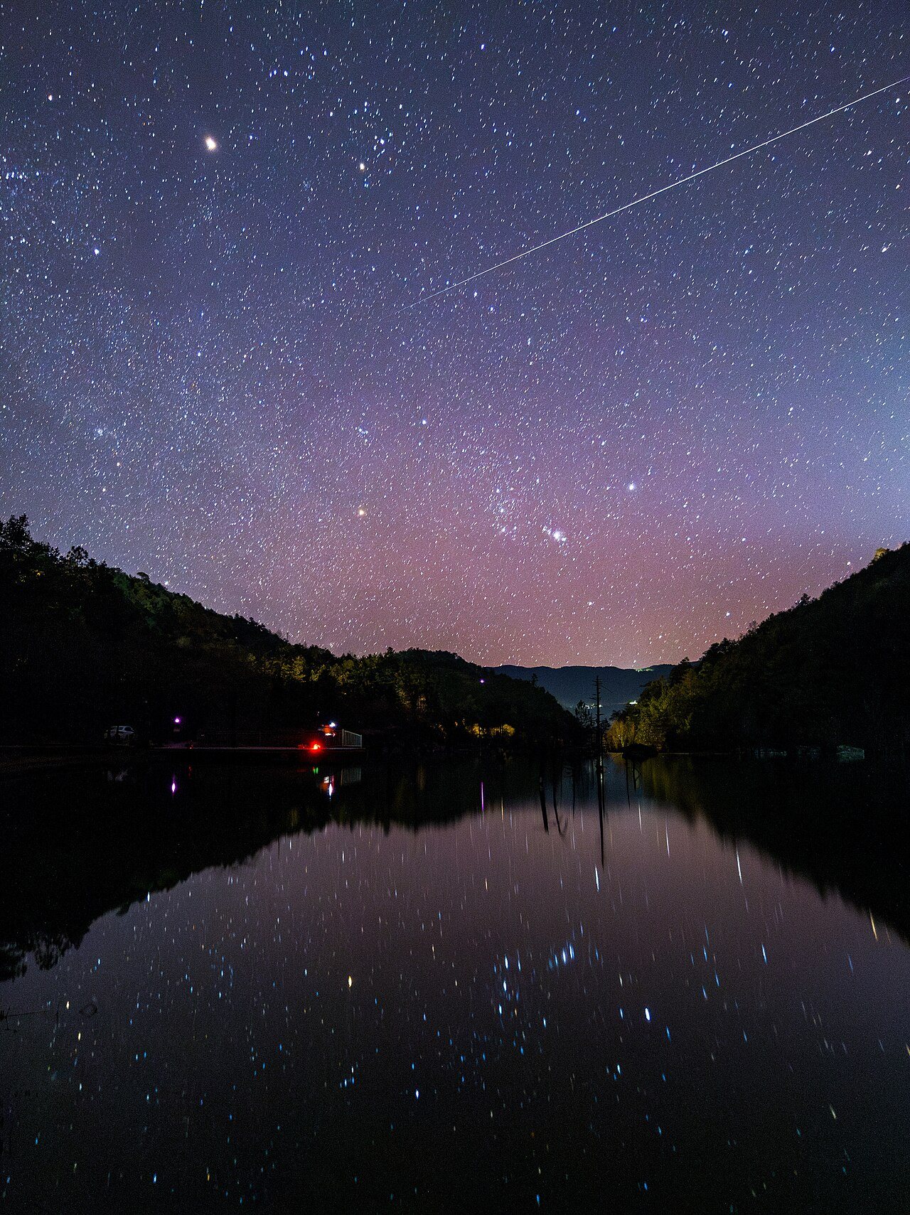 湖の上の夜空を明るく照らす流れ星