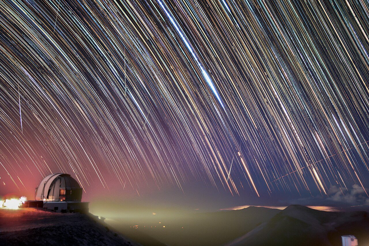天文台のドームの上で星が円を描く夜空と何本かの流れ星