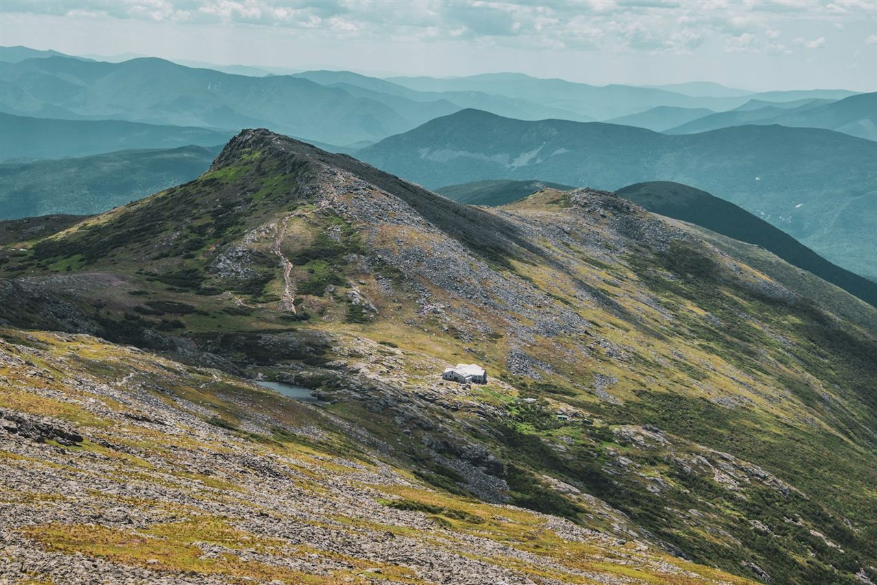 緑と岩の斜面に建つ白い小屋