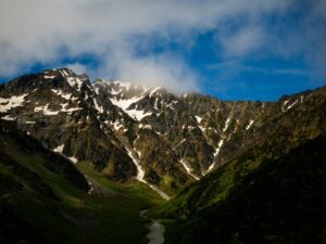雪の残る山並みと緑の谷