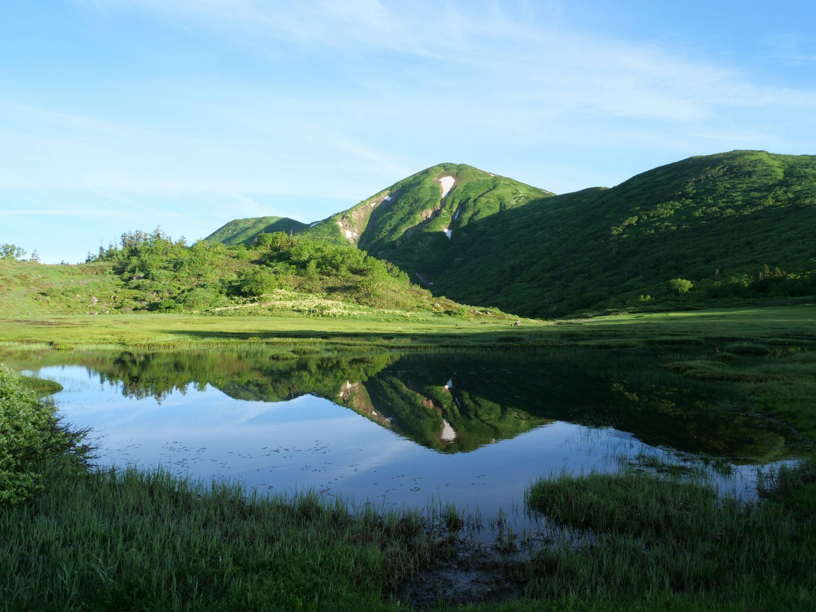 草原の池に映る緑の山