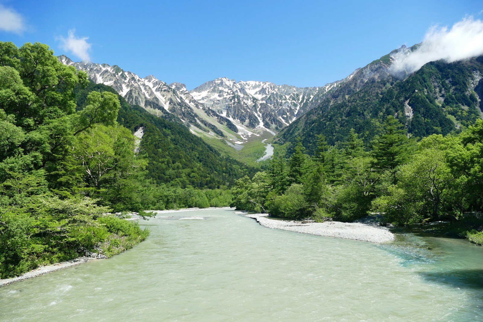 青く澄んだ梓川と雪の残る山