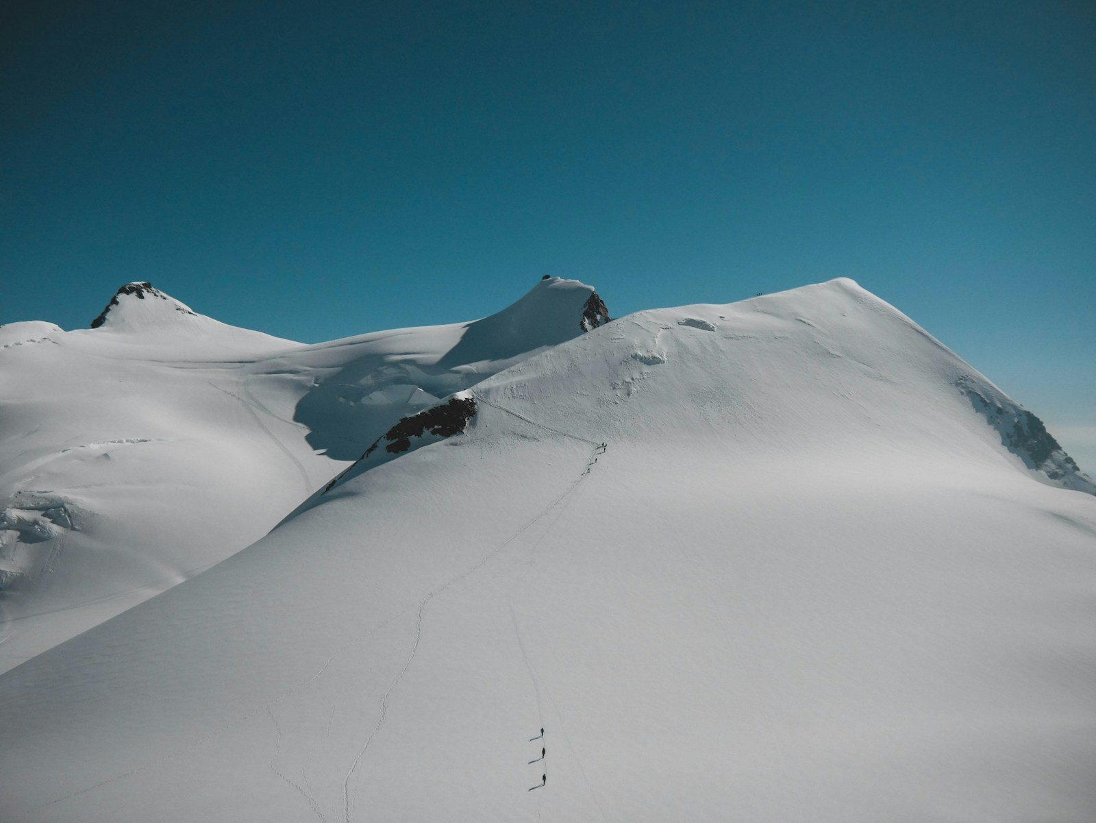 雪山の斜面を歩く小さな人影