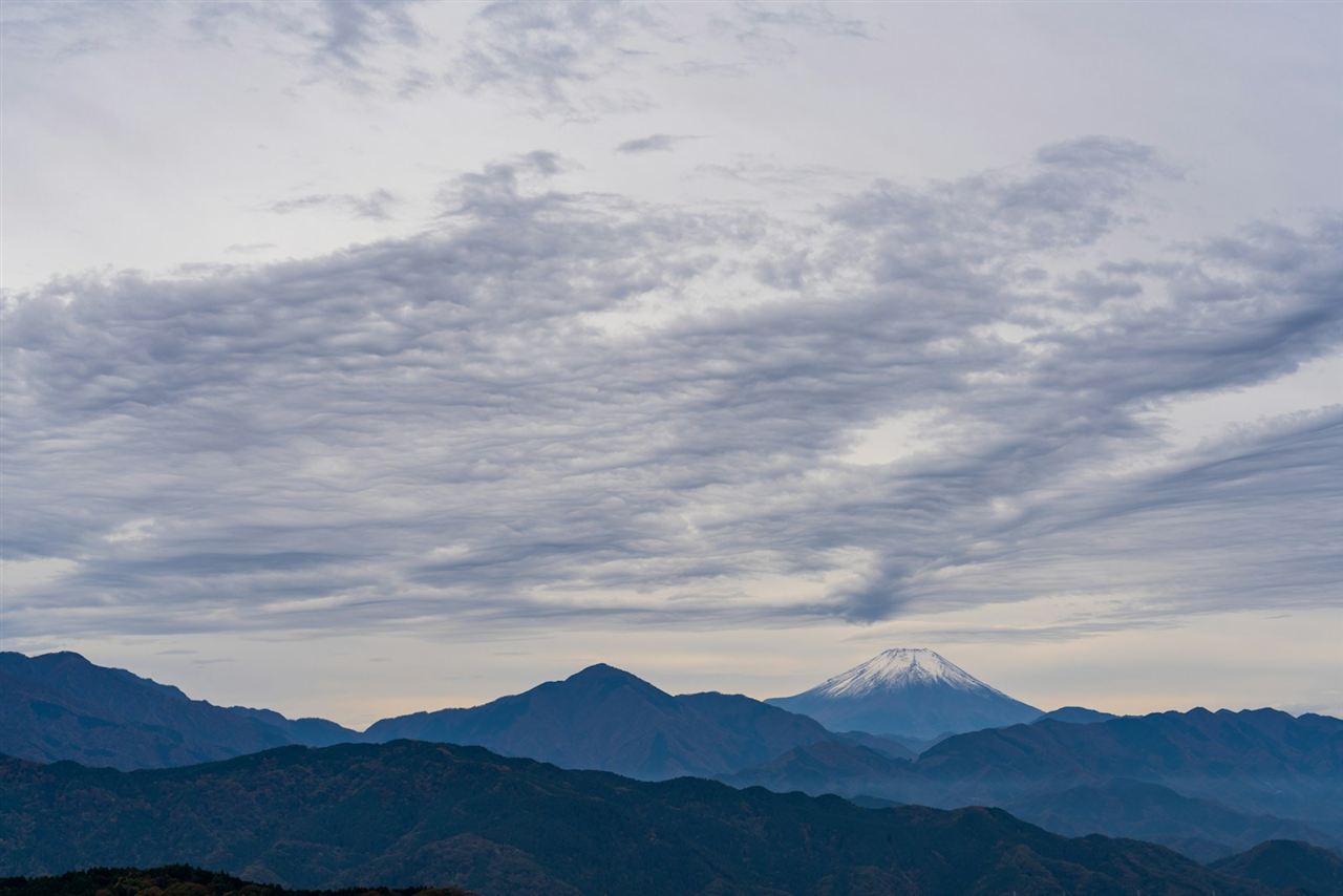 うろこ雲の下に連なる山並みと富士山