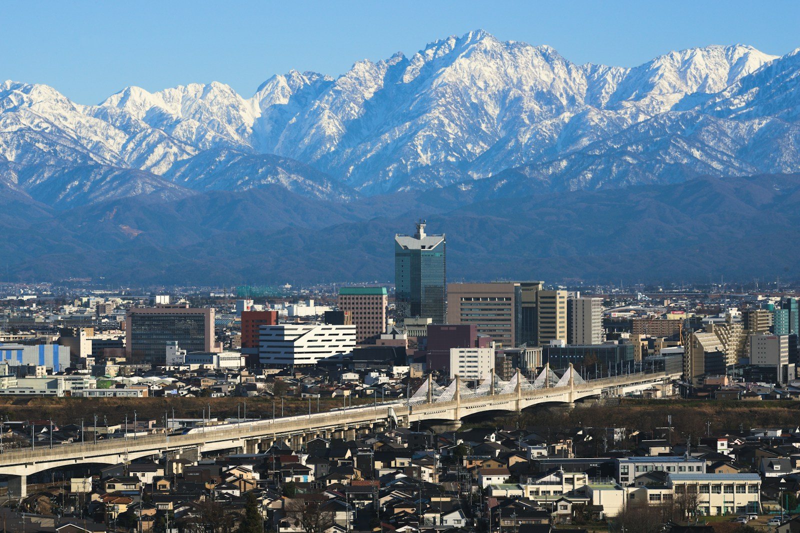 富山の市街地の向こうに連なる雪の立山連峰